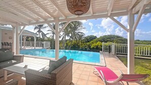 A covered pool area with a view of palm trees and a clear sky. - Beautiful villa with sea view and infinity pool (Saint François)