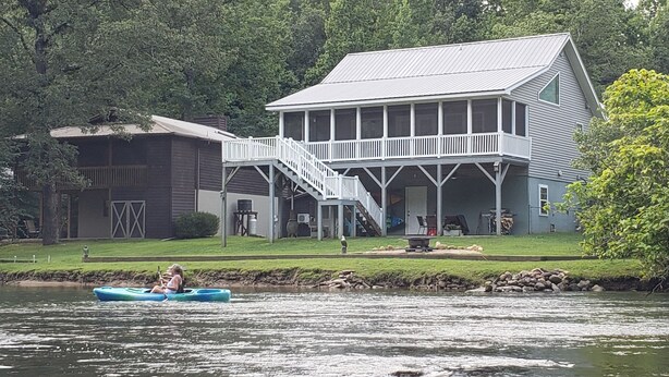 A large house with a covered porch and a staircase leading to a second floor. - Winter in the mountains, fishing by the fire pit. Murphy and the Casino nearby. (Murphy)
