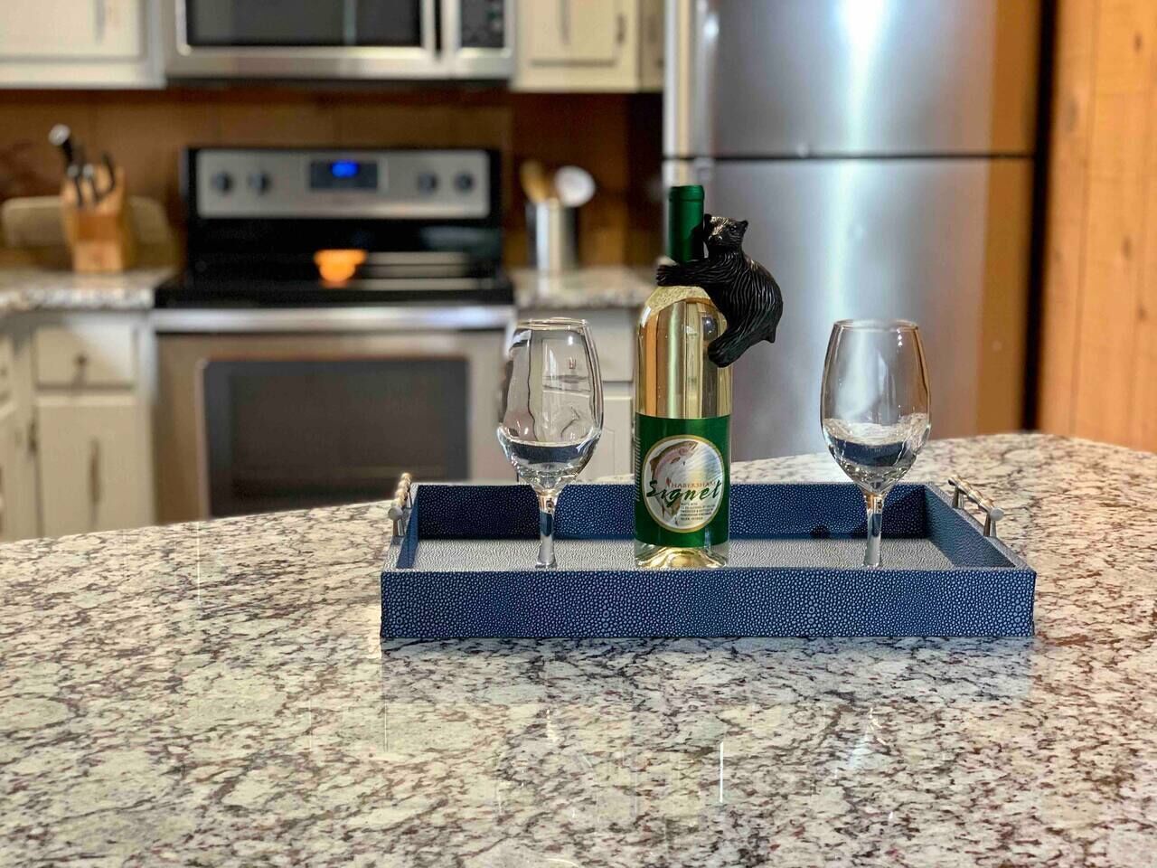 Una encimera de cocina con una botella de licor y dos vasos sobre una bandeja azul.
