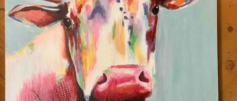 A painting of a cow on a wooden floor.