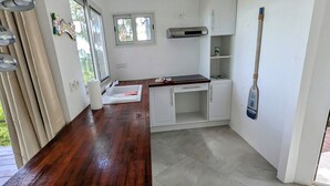 A modern kitchen with white cabinetry, a wooden countertop, and a built-in stove.