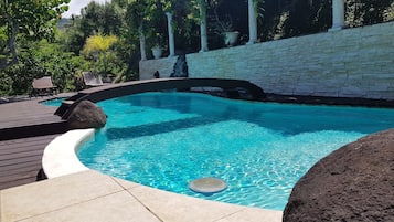 En pool med stenvæg og træterrasse.