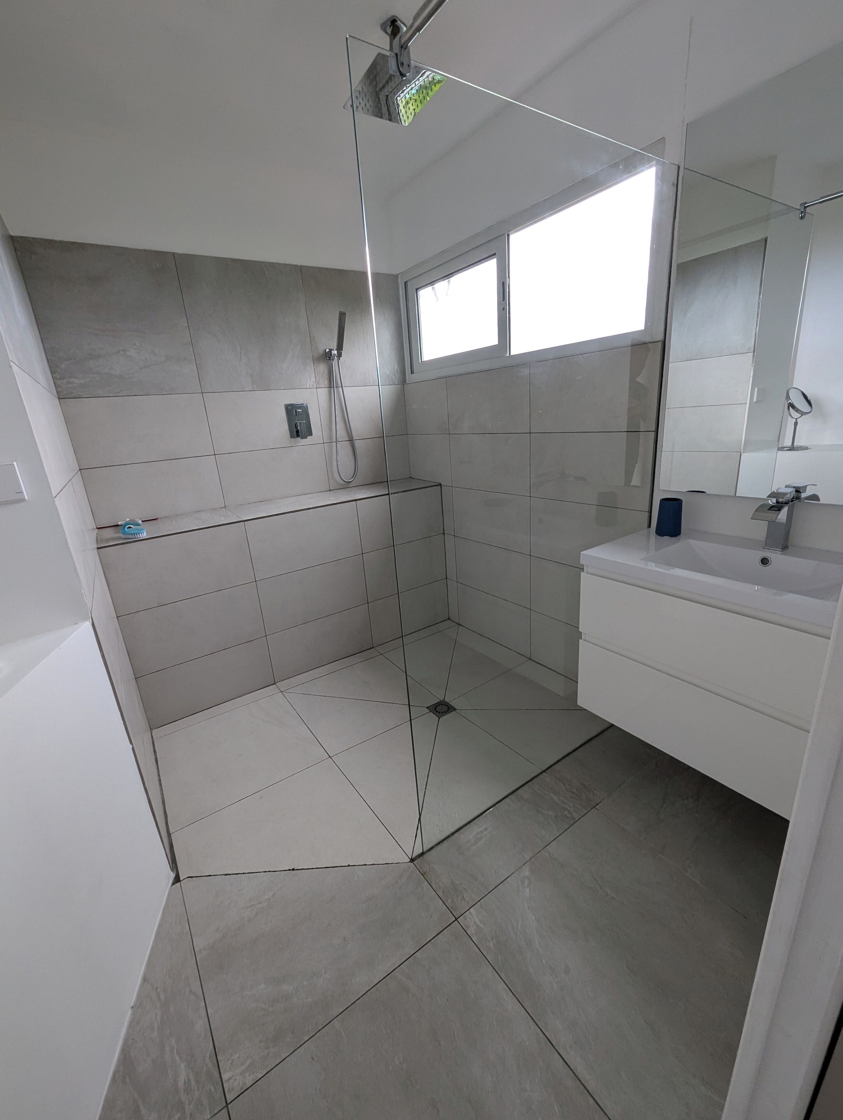 A modern bathroom with a shower, a sink, and a mirror.