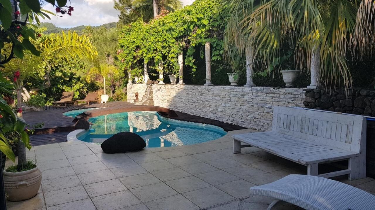 A pool area with a stone wall, lounge chairs, and potted plants.