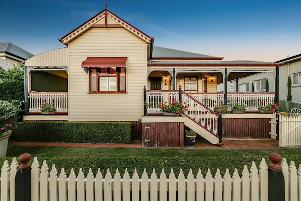 A two-story house with a porch, a staircase, and a white picket fence.