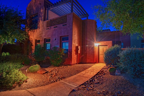 A modern building with a red facade, a visible entrance, and a well-maintained garden with cacti and shrubs. - Great condo for exploring Tubac & surroundings! (Tubac)