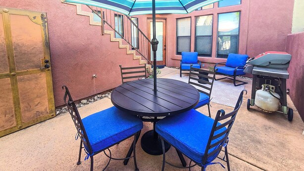 An outdoor patio with a round table and chairs, a grill, and a blue-striped umbrella. - Great condo for exploring Tubac & surroundings! (Tubac)