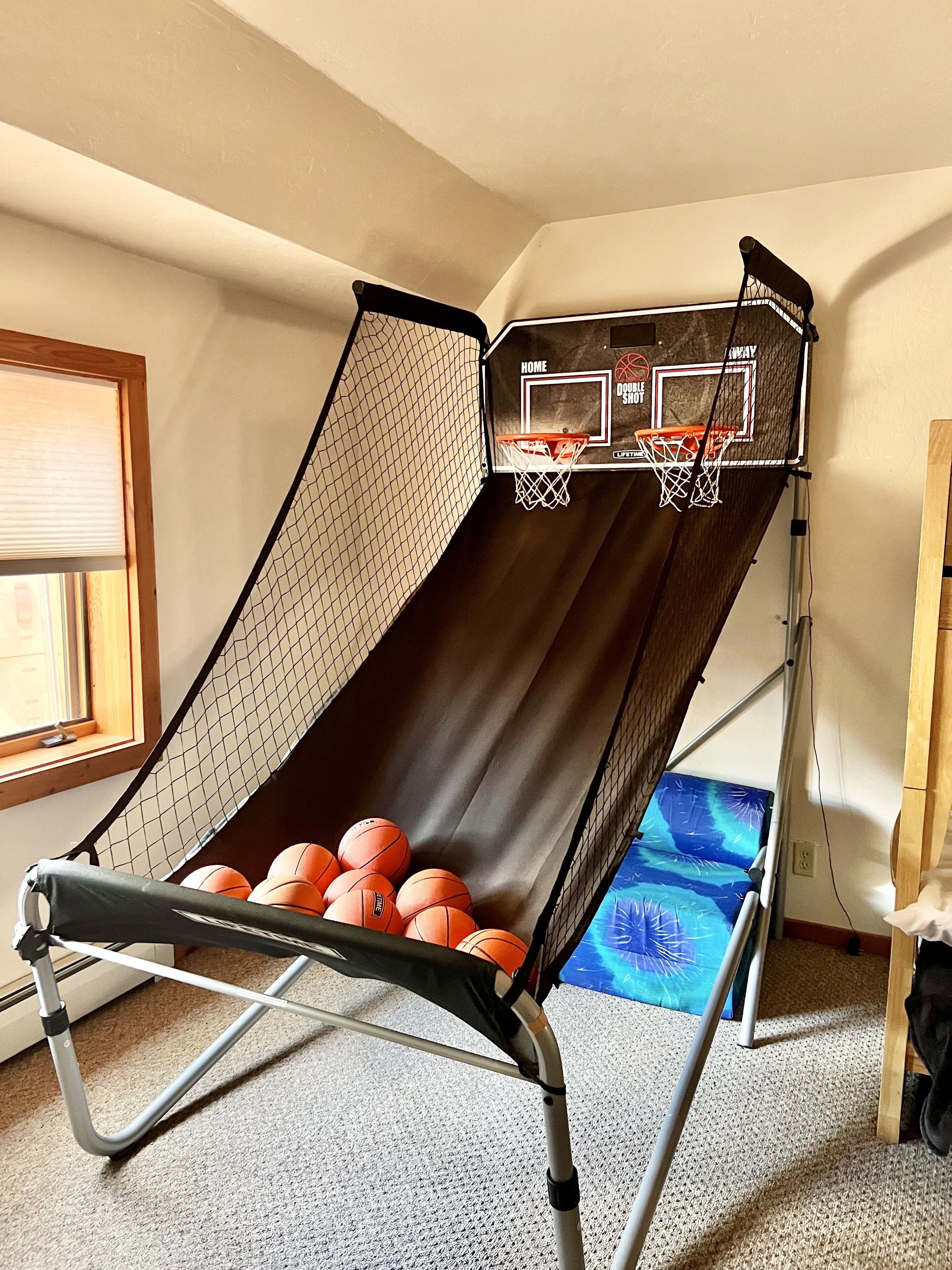 Un aro de baloncesto con red, un tobogán y varias pelotas de baloncesto.