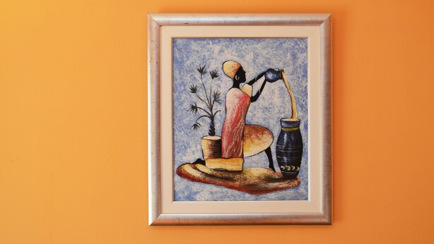 A framed artwork on an orange wall.