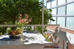 A table with a bowl of fruit and a vase of flowers, set against a backdrop of a building and greenery. - LaidBack Apartments - Two Bedroom Apartment with Terrace and Sea View (Orebic)