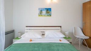 A neatly arranged bedroom with a bed, a nightstand, a chair, and a wall-mounted lamp. - LaidBack Apartments - Comfort One Bedroom Apartment with Balcony and Sea View (Orebic)