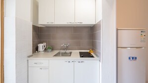 A small kitchenette with white cabinets, a stainless steel sink, a kettle, and a refrigerator. - LaidBack Apartments - Comfort One Bedroom Apartment with Balcony and Sea View (Orebic)
