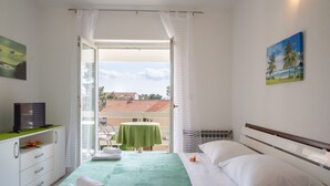 A hotel room with a bed, a TV, a desk, and a balcony with a table and chairs. - LaidBack Apartments - Comfort One Bedroom Apartment with Balcony and Sea View (Orebic)