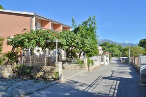 Eine Wohnstraße mit Häusern, blauem Himmel und Bergen im Hintergrund.