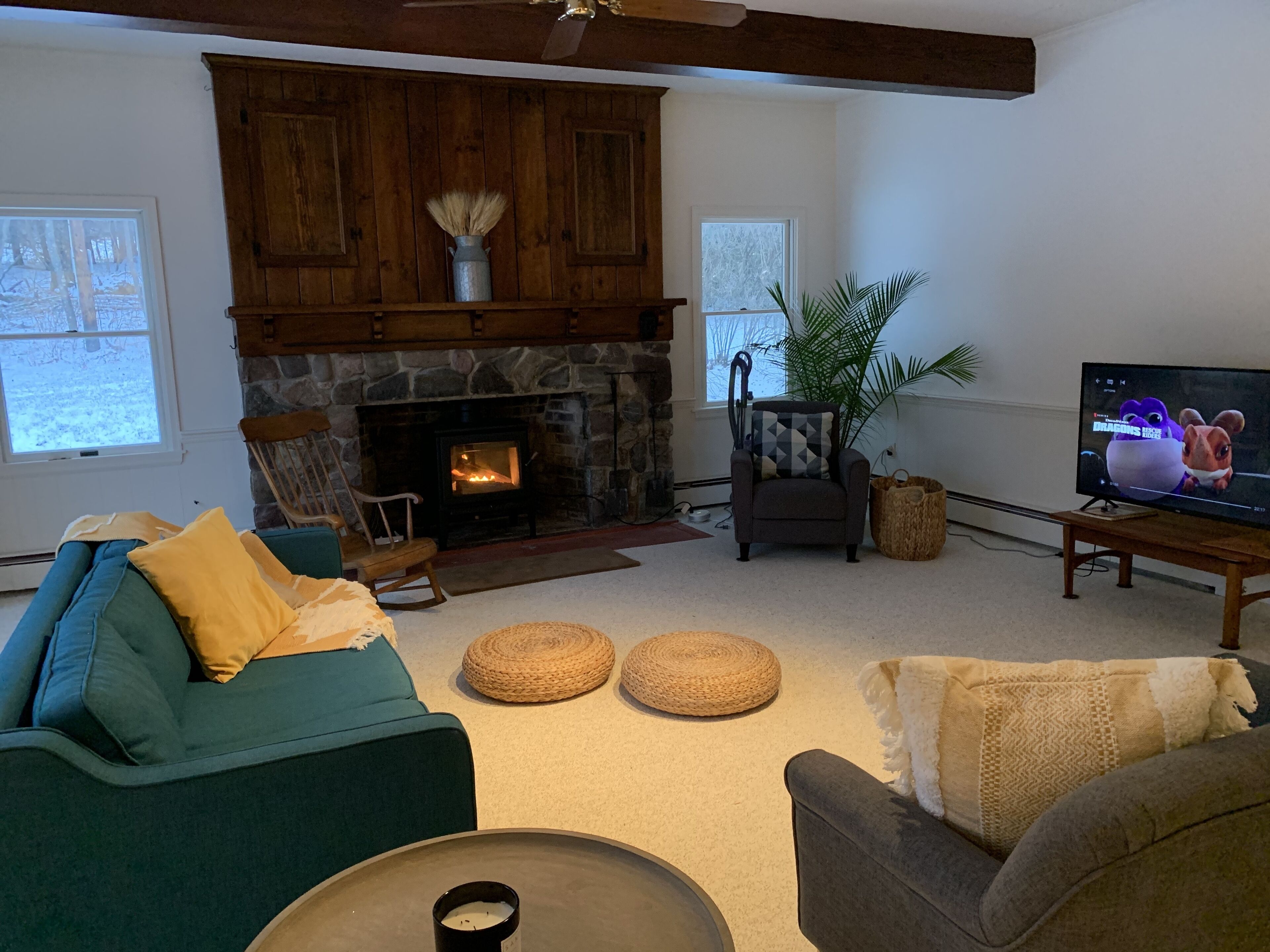 Un salon chaleureux avec une cheminée en pierre, un téléviseur et des fauteuils confortables.