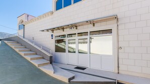 Un edificio con una escalera que lleva a una puerta, una barandilla de metal y un cielo despejado.
