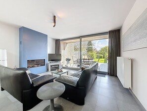 Un salon moderne avec un téléviseur, un canapé et une petite table.