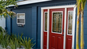 A red door with glass panels and a sign reading "Palm Cottage."