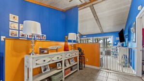 A room with a blue and orange color scheme, featuring a white console table with drawers and shelves, a lamp, and framed photos. - Waterfront 3BR/3BA Getaway: Beach, Dock, Firepit! AMAZING Sweeping VIEWS! (Heathsville)