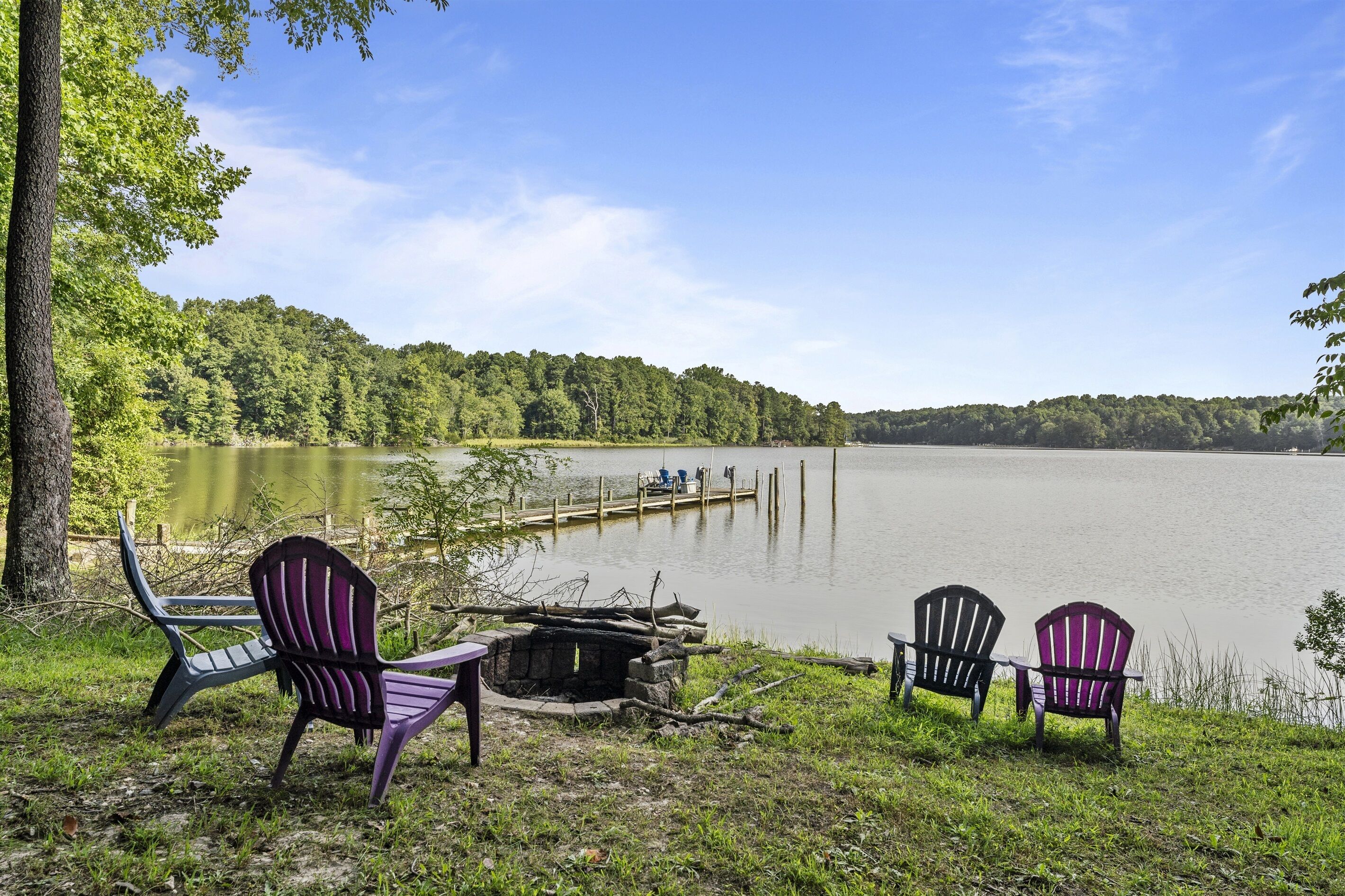 A lakeside view with two Adirondack chairs and a small dock.