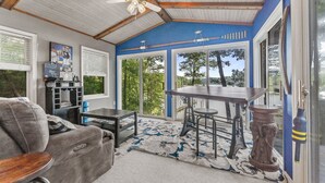 A sunroom with a ceiling fan, large windows, a dining table, and a sofa. - Waterfront 3BR/3BA Getaway: Beach, Dock, Firepit! AMAZING Sweeping VIEWS! (Heathsville)
