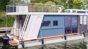 Ein Hausboot mit Deck, Fenstern und blau-weißer Farbgebung.