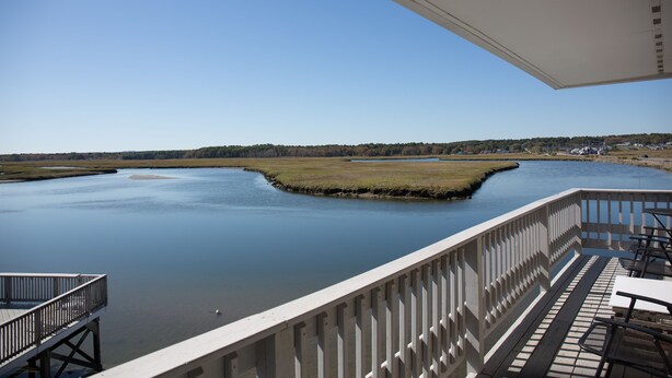 A deck with a view of a calm river and distant trees. - Sunset Views over Rachel Carson Preserve. Relax steps from Wells Beach. (Wells)