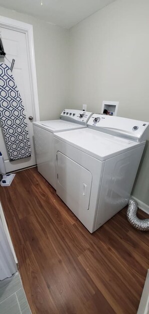 A laundry room with two front-loading washing machines, a white door, and a patterned curtain.