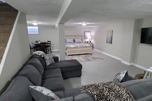 A modern living room with a sectional sofa, a bed, and a dining area.