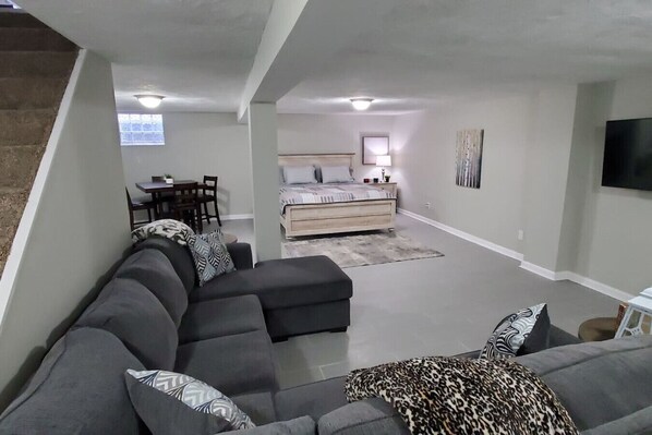 A modern living room with a sectional sofa, a bed, and a dining area.