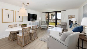 A modern living room with a dining area, a sofa, and a TV.