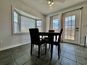 Un espace repas comprenant une table et des chaises, de grandes fenêtres et une porte.