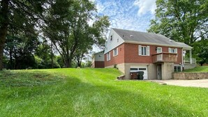 Ein zweistöckiges Backsteinhhaus mit Veranda und Garage.