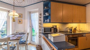 A modern kitchen with wooden cabinets, a built-in oven, and a dining area with a table and chairs. - Amazing apartment in Friedrichskoog with WiFi (Friedrichskoog)