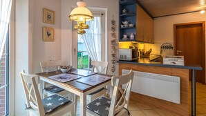 A dining area with a table and chairs, a hanging light fixture, a kitchen counter with utensils, and a radiator. - Amazing apartment in Friedrichskoog with WiFi (Friedrichskoog)