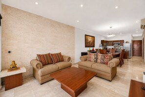 A modern living room with two sofas, a coffee table, and a kitchen in the background.