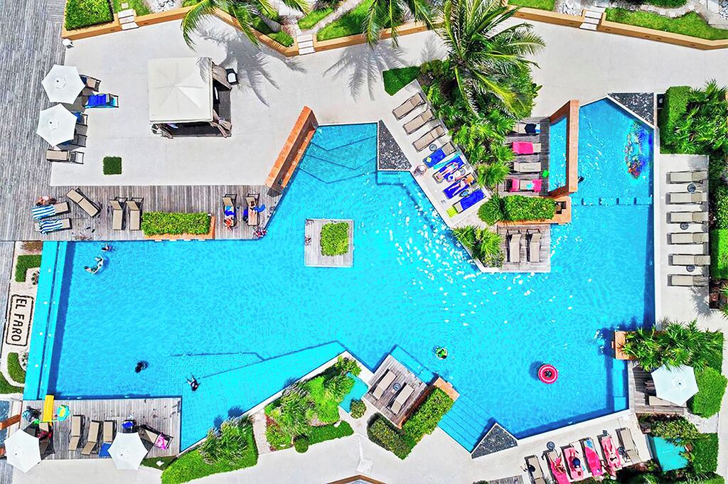 A large outdoor swimming pool with multiple lounge areas and sunbeds.