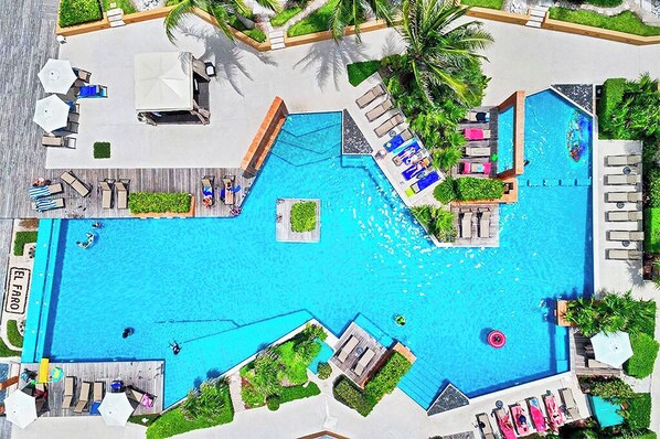 Uma piscina grande ao ar livre com várias áreas de estar e espreguiçadeiras.