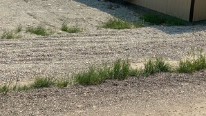 Einbungalow mit einem Schotterweg, einer kleinen Veranda und einer Klimaanlage.
