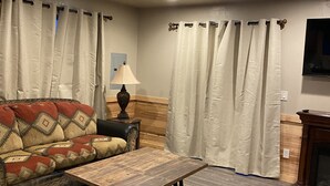 Ein Wohnzimmer mit Sofa, Couchtisch, Vorhängen, einer Lampe und einem Kamin.
