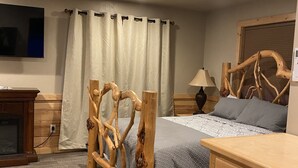 Ein Schlafzimmer mit einem hölzernen Bettgestell, einem Nachttisch, einer Lampe und einem an der Wand befestigten Fernseher.