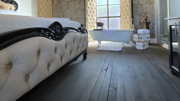 Ein Schlafzimmer mit einem großen Bett, einer Badewanne und Steinwänden.