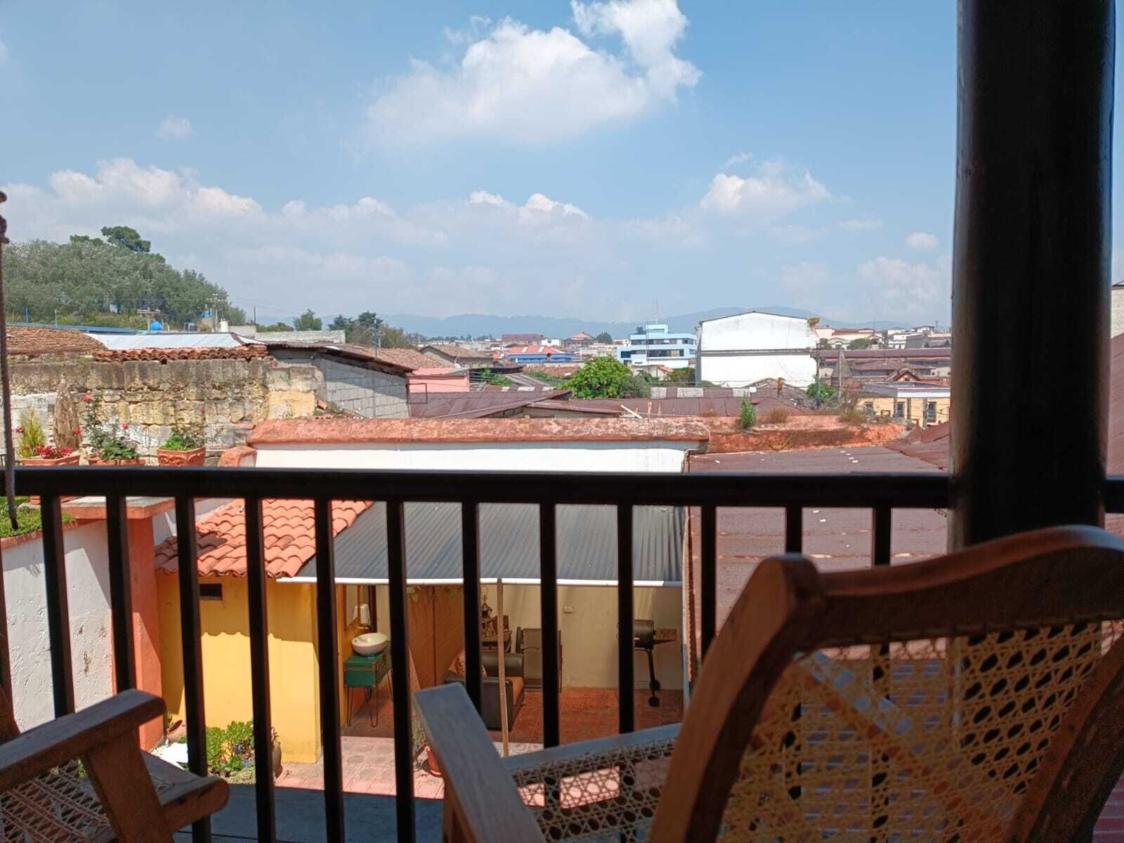 Un balcón con vista a una zona residencial, que incluye casas y edificios.