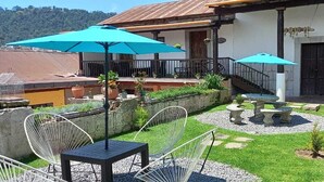 Eine Terrasse im Freien mit Sitzgelegenheiten, Sonnenschirmen und einem Steinknebelbrunnen.