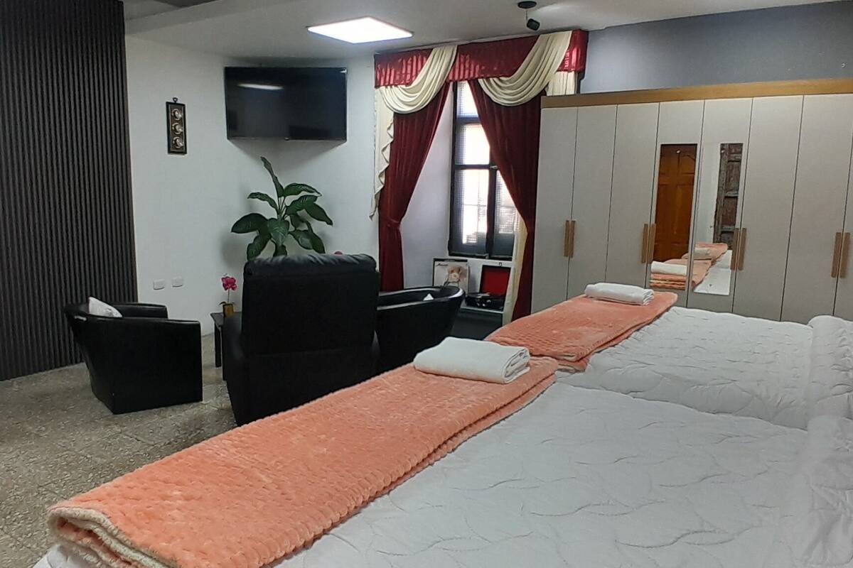 A hotel room with a bed, a desk, a chair, a TV, and a wardrobe.