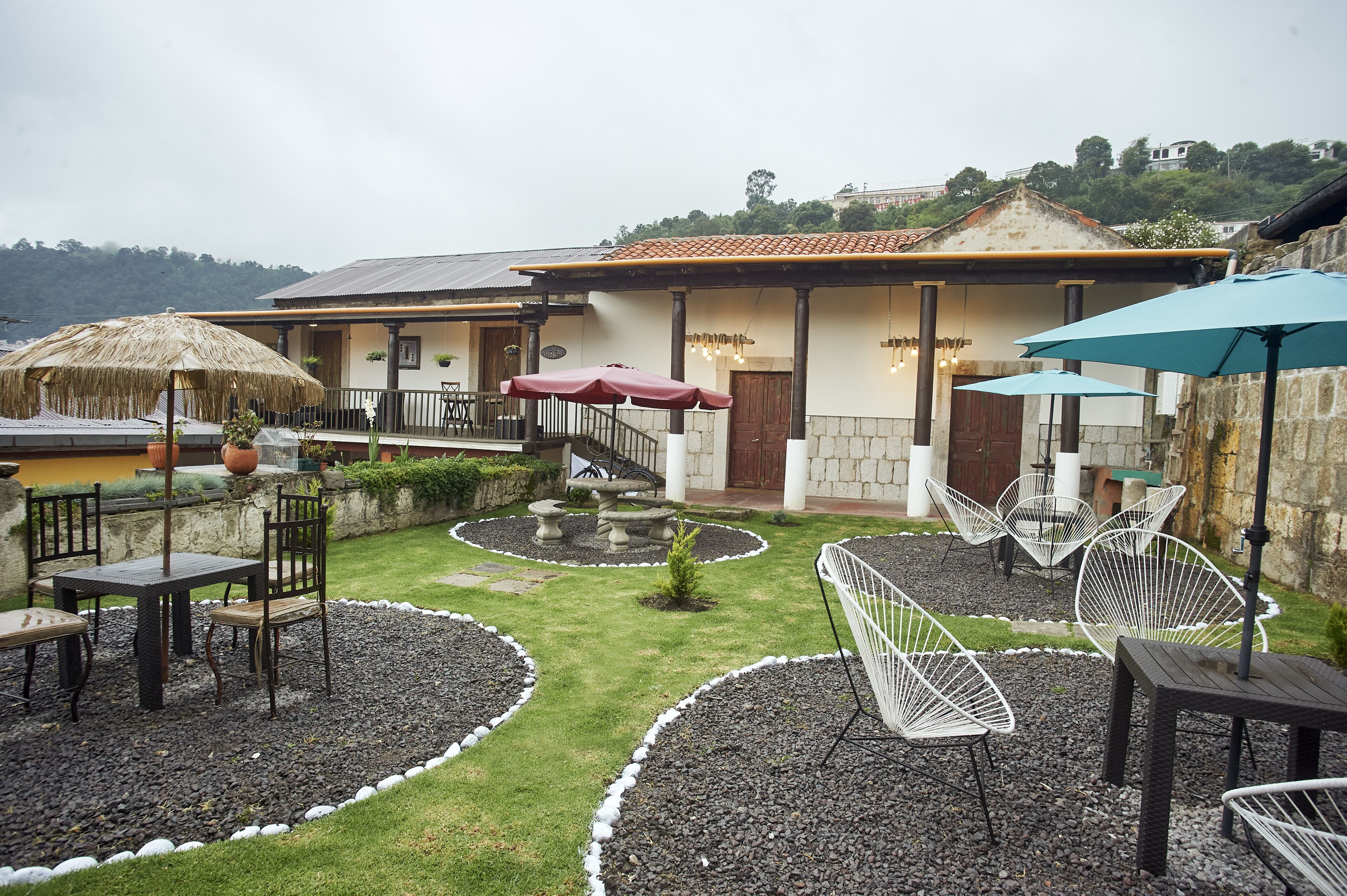 A courtyard with outdoor seating, a stone staircase, and a building with a tiled roof.