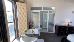 Ein Zimmer mit Badewanne, Holztisch, Bett und Kleiderschrank.