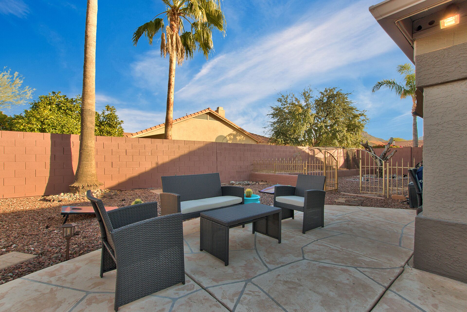 An outdoor patio with wicker furniture, a cactus, and a brick wall.
