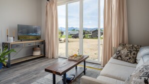 A living room with a TV, a sofa, a coffee table, and a view of the outdoors. - Modern Home w/ Great Private Views, Hot Tub & Sauna (Tabernash)