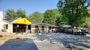 A motel with a yellow awning, a covered front porch, and a parking area with a yellow curb. - Super 8 By Wyndham Asheville Biltmore (Asheville)